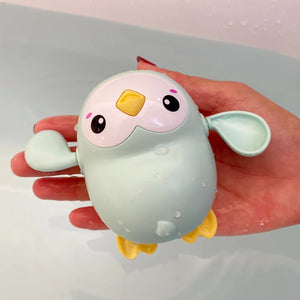 Hand holding a cute cartoon-like bird figurine with a light green body and yellow accents.