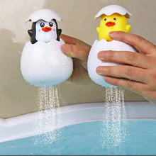 Load image into Gallery viewer, Two baby penguin and duck bath toys in egg-shaped containers with water flowing out, held over a bathtub.