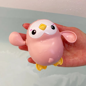 Pink and yellow bird-shaped toy held in a hand against a light background
