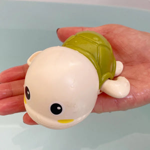 Toy turtle held in a hand against a light background