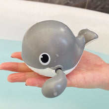 Load image into Gallery viewer, Gray whale-shaped bath toy held in a hand with a blurred bathtub background