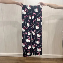 Load image into Gallery viewer, Navy blue pajama pants with Hello Kitty pattern held up against a neutral wall.