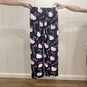 Navy blue pajama pants with Hello Kitty pattern held up against a neutral wall.
