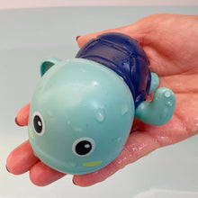 Load image into Gallery viewer, Hand holding a small blue and green toy with a shell-like top