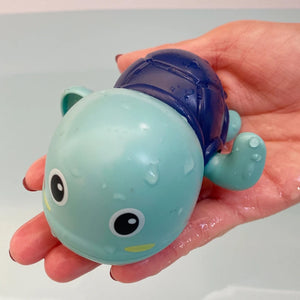 Hand holding a small blue and green toy with a shell-like top
