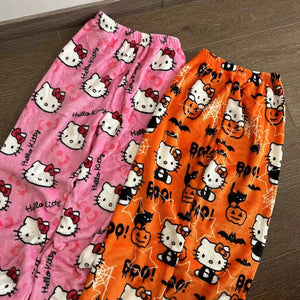 Two pairs of pajama pants with Hello Kitty designs on a wooden floor.