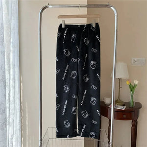 Black pants with white cat prints hanging on a rack in a room.