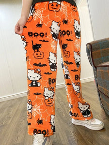 Orange Halloween-themed pants with Hello Kitty design worn by a person indoors.